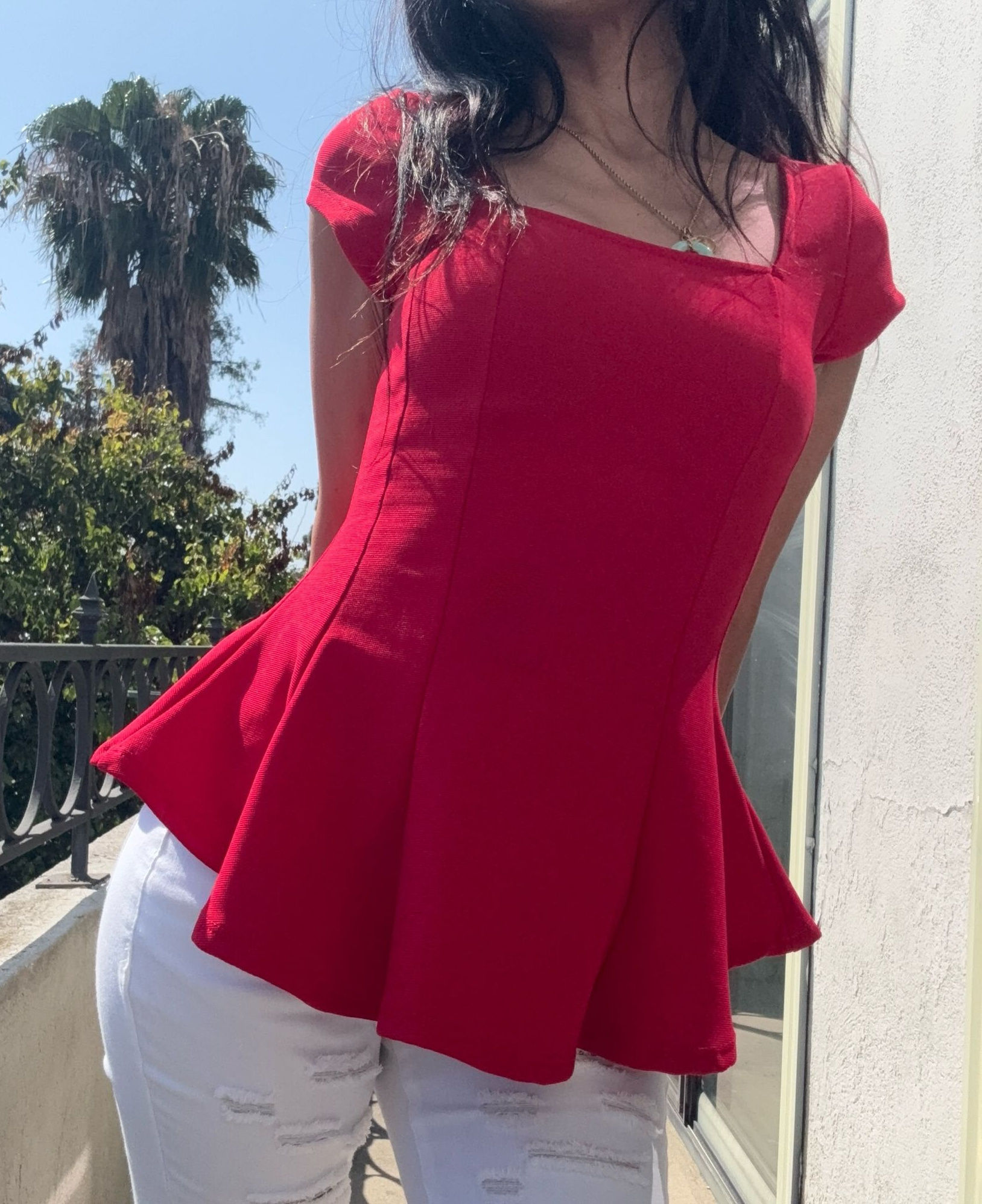 Red sculpted peplum top with a fitted waist and softly flared hem.