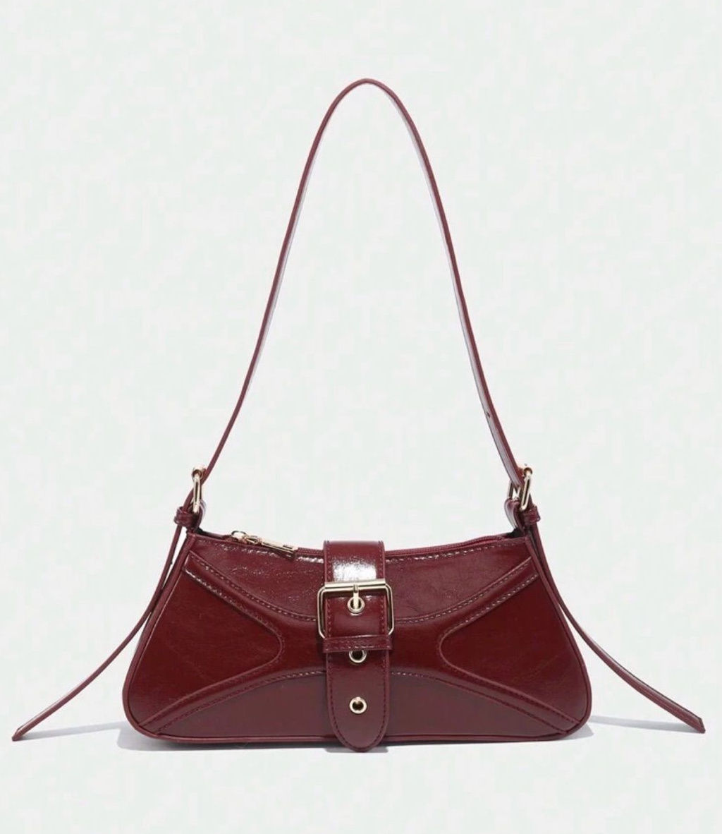 Burgundy elongated shoulder bag with a slender strap and centered buckle detail.