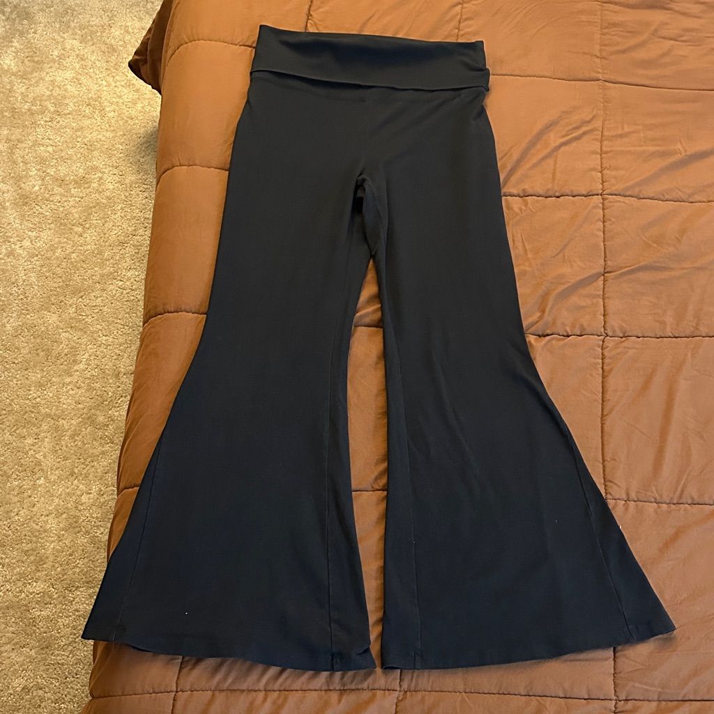 Black foldover-waist flare yoga pants laid flat, showing the wide waistband and flared legs.