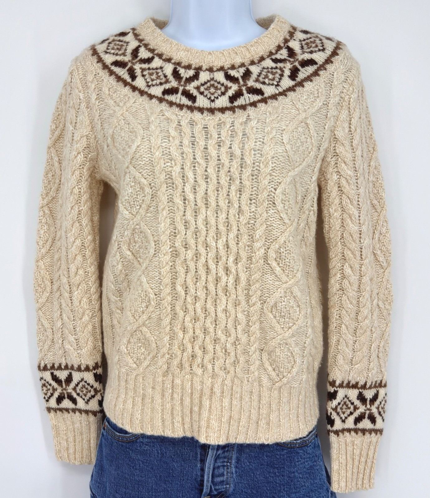 Cream cable-knit Fair Isle sweater styled with blue denim jeans.