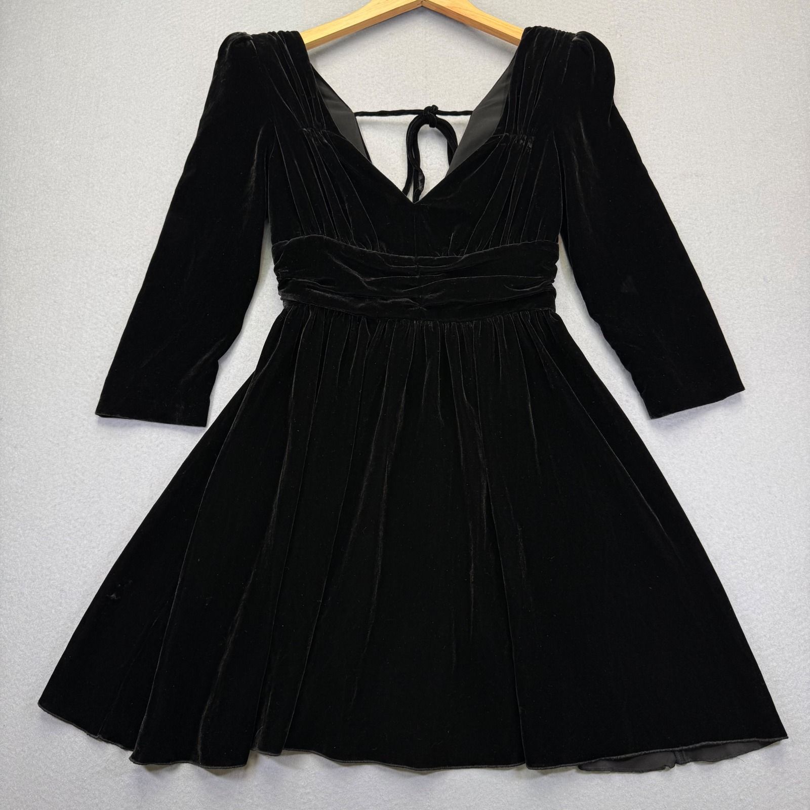 Black velvet ruched mini dress with sleeves and a softly flared skirt.