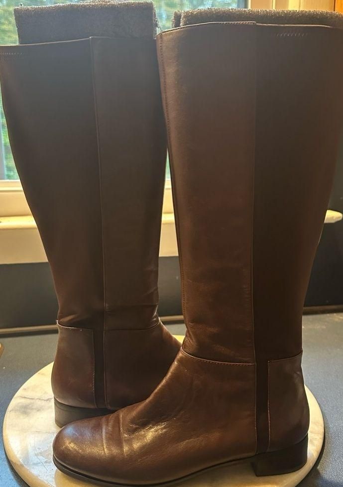 Brown leather knee-high riding boots in natural window light.