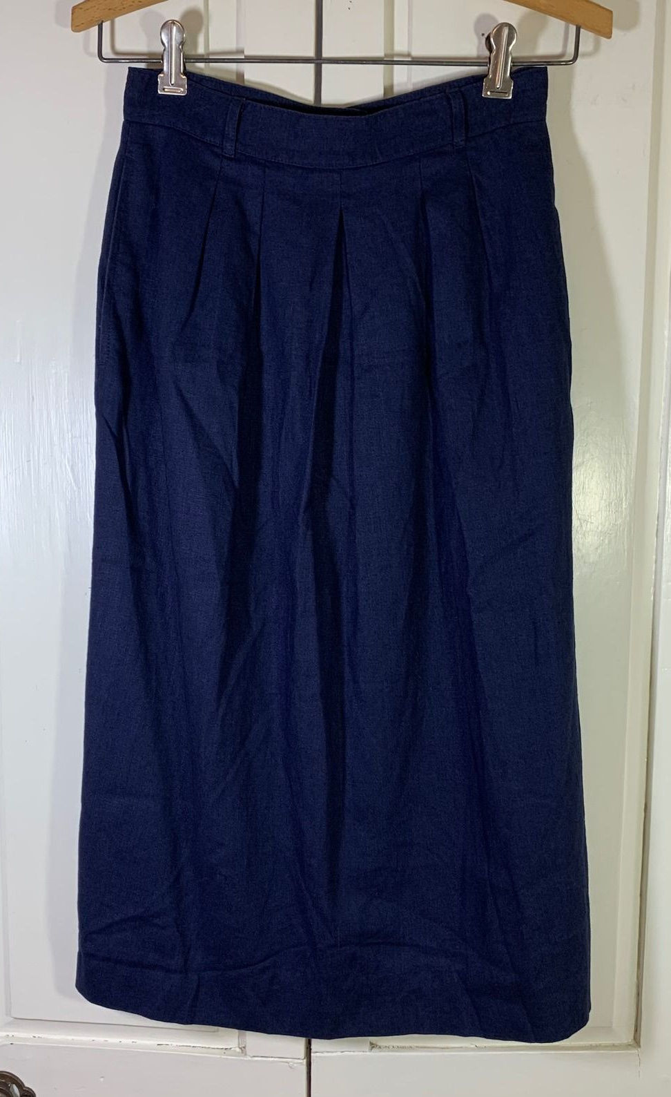 Navy pleated midi skirt with a visible waistband and softly folded hem.