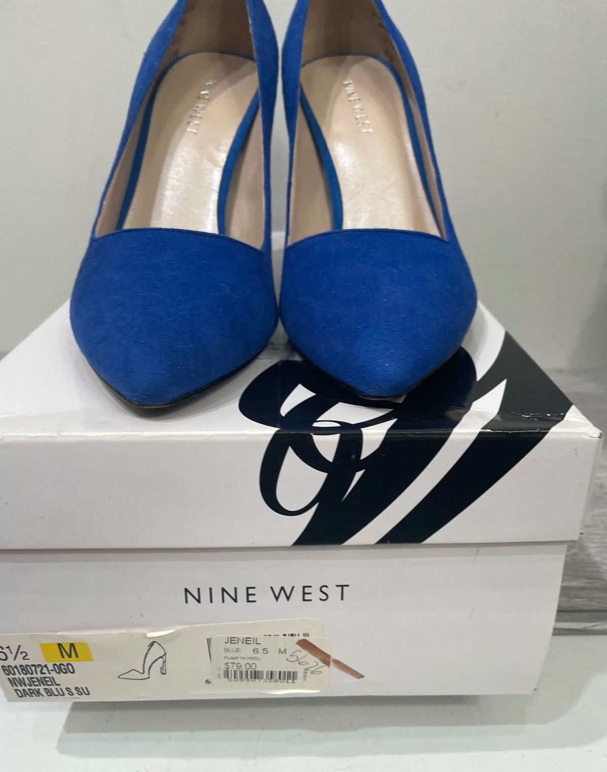 Cobalt-blue suede pointed-toe pumps photographed on a shoe box.