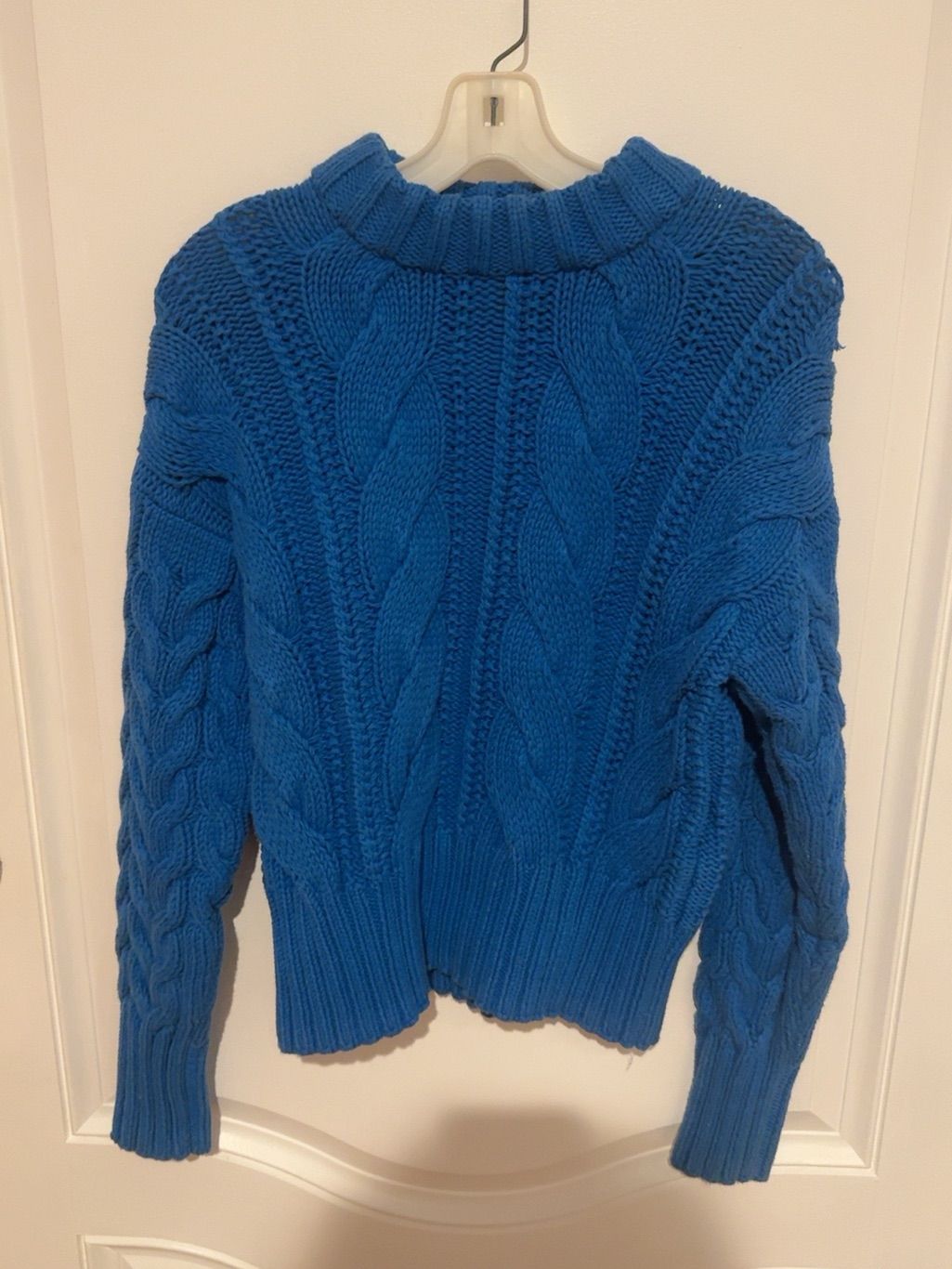 Vivid cobalt-blue chunky cable-knit sweater with pronounced textured braids and ribbed trim.