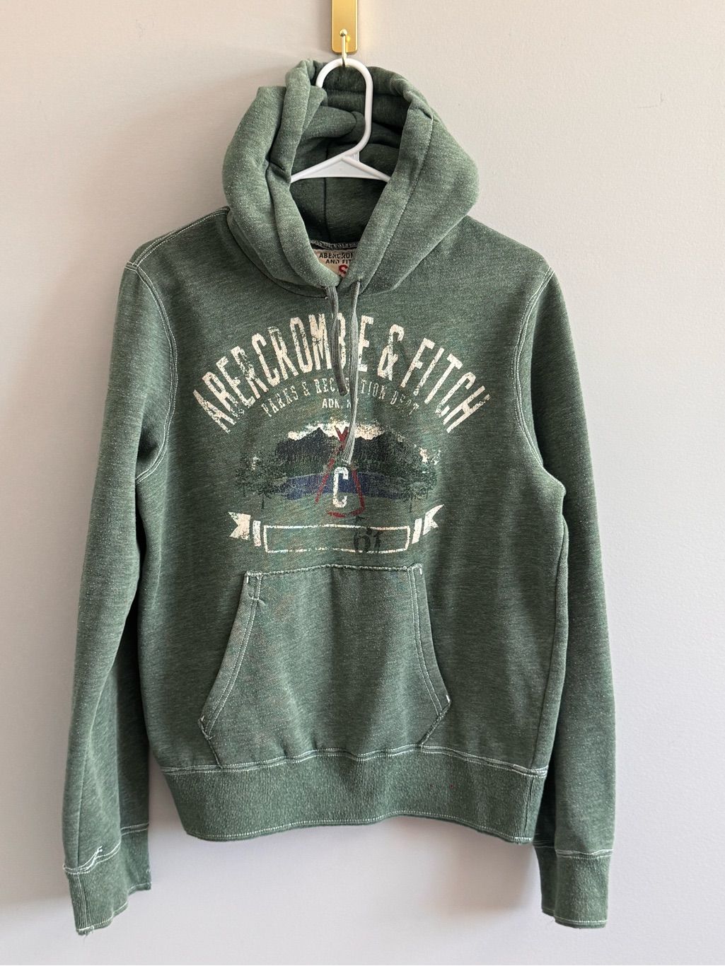 Distressed green hoodie with a faded collegiate-style graphic and colorful emblem.