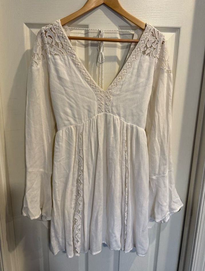 Ivory lace babydoll mini dress with an empire waist and sheer long sleeves.