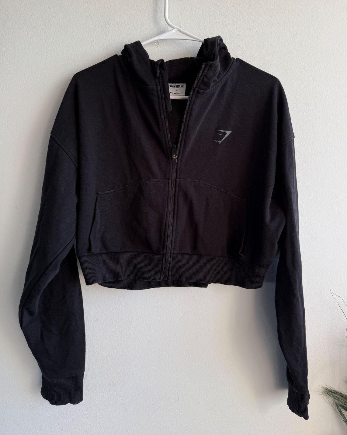 Black cropped athletic full-zip hoodie with a boxy silhouette and front pockets, shown on a hanger.