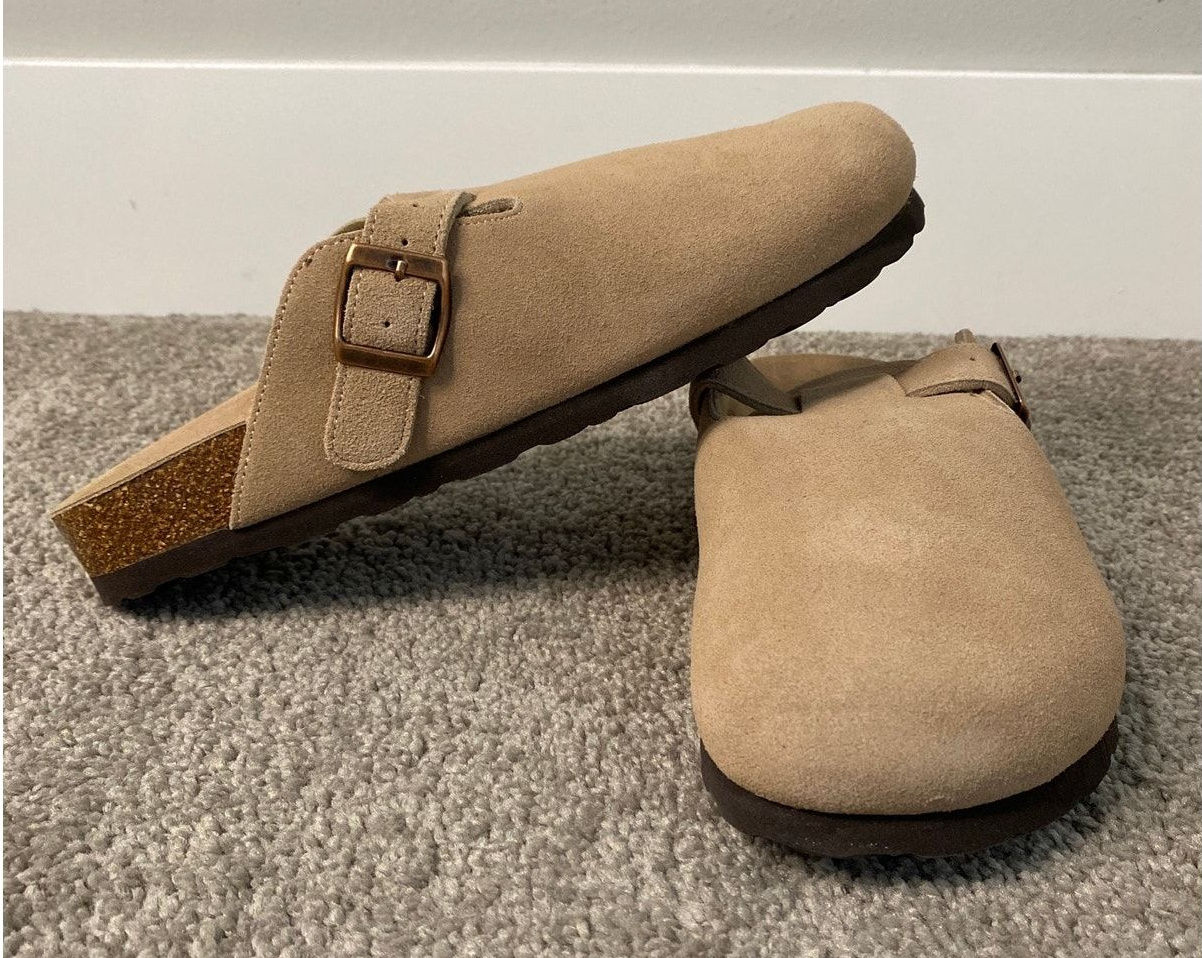 Taupe suede buckle clogs shown in a clear full-shoe view.