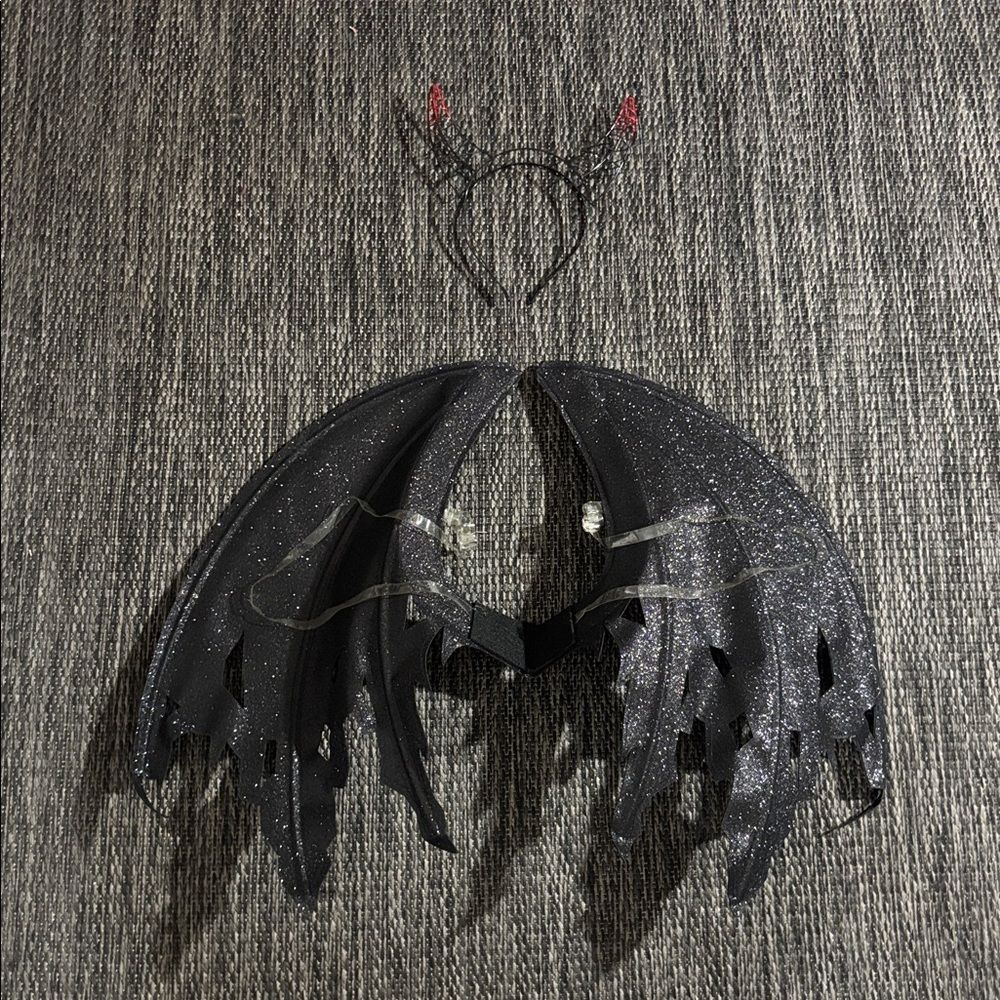 Sheer black fairy wings with a devil-horn headband against a gray background.