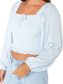 light blue long-sleeved crop top with ruffled edges.