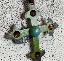 Green glazed metal cross with turquoise center on a copper ball chain. 18”
