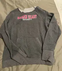 Cozy gray sweatshirt featuring Sacred Heart University logo in red and white.
