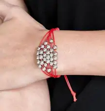 silver beads are threaded along row after row of shiny red cording around the wrist