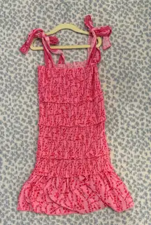 Charming pink dress with ruffle details. Features playful bow straps. Perfect for special occasions.
