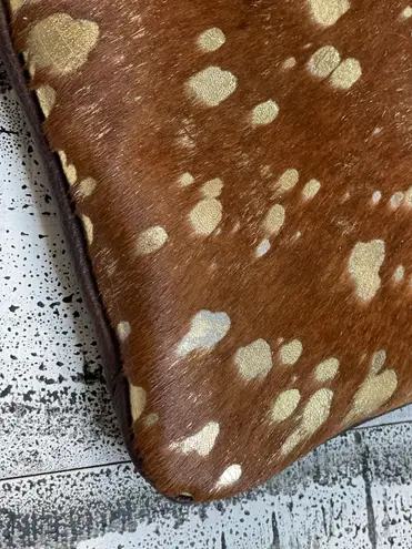 Brown cowhide with gold acid wash. 10”x6” wristlet with removable strap.