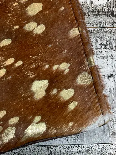 Brown cowhide with gold acid wash. 10”x6” wristlet with removable strap.