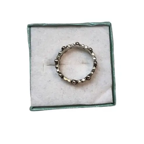 An antiqued collection of silver studs delicately coalesce into a dainty band of Size 6