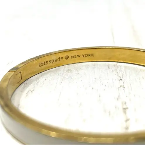 Kate Spade gold tone and white enamel hinged bangle bracelet