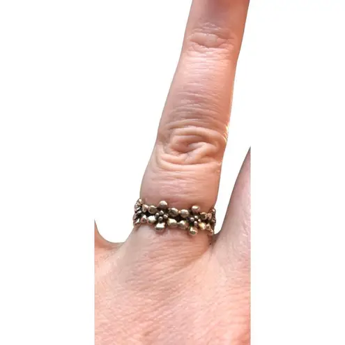 An antiqued collection of silver studs delicately coalesce into a dainty band of Size 6