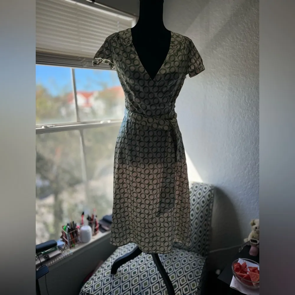 The dress in the image is a wrap style, with a geometric print of green circles - Image 3