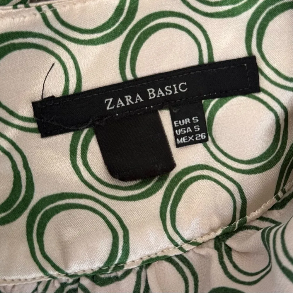 The dress in the image is a wrap style, with a geometric print of green circles - Image 5