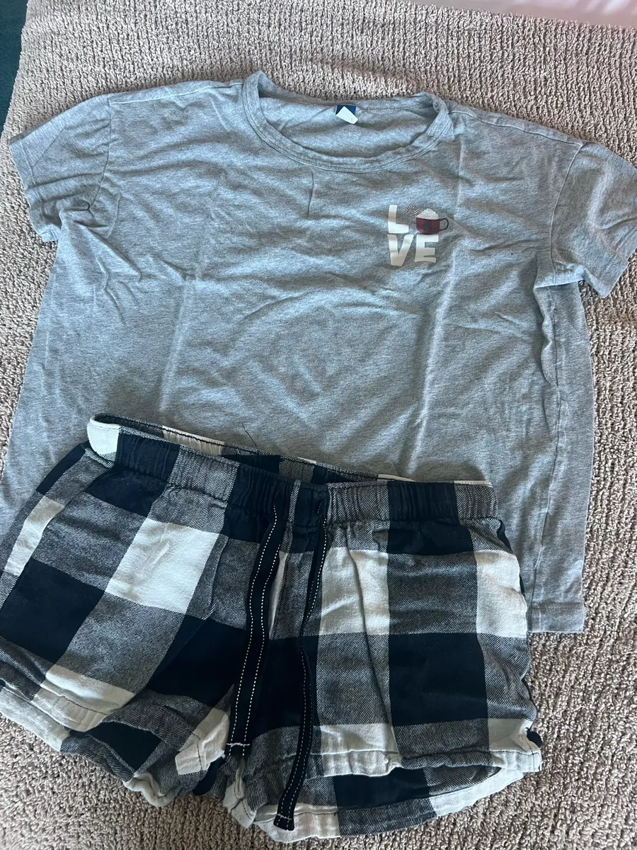 Cozy set featuring a gray short sleeve tee with a small "LOVE" graphic. Includes black and white plaid drawstring lounge shorts. Soft, casual pieces perfect for lounging or sleepwear.