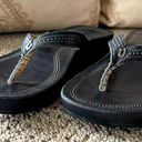 Olukai Okukai Women’s Leather Flip Flop Thong Sandals in Black with Detail. Photo 1