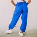 These Three Boutique. High-rise pant. Windbreaker material. Has pockets and can be worn as joggers or straight-leg style! Color: Blue. Size: Small. Photo 2