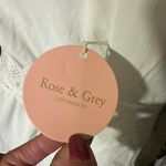 Rose & Grey LOS ANGELES white lace V-neck long sleeve shirt top peplum tie cuff  New with tag  Smoke and pets free  Same day shipping Elevate your wardrobe with this stunning white lace blouse from . The V-neckline and long sleeves add a touch of elegance to this top, while the peplum and tie cuff details create a flattering silhouette. The angel character and rose theme make it perfect for any occasion, from casual outings to formal events.   Crafted from high-quality lace fabric, this blouse features adjustable features and is available in size S. The solid pattern and delicate lace accents make it a versatile piece that can be paired with any bottom. Whether you're dressing up or down, this  blouse is sure to turn heads. Photo 2