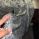 No Boundaries A black and white patterned “” blouse with pretty white lace detailing and stylish side openings. It has a light, airy, flowy fit that pairs perfectly with pants or a cute casual outfit. Size: Medium (7–9). Photo 1