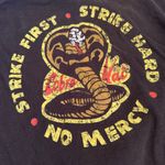 •COBRA KAI KARATE KID “STRIKE FIRST STRIKE HARD” UNISEX T Photo 1