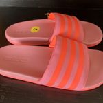 Adidas ADILETTE COMFORT K sandals pink orange super soft comfy light weight NWT New with tag Same day shipping Smoke and pets free Get ready to step up your style with these Adilette Comfort K sandals! These sandals are perfect for those who want to look fashionable while staying comfortable. With a super soft and lightweight design, these sandals are perfect for all-day wear. The pink and orange striped pattern adds a pop of color to your outfit, making them a great choice for any occasion. These sandals come in a UK shoe size 5, US shoe size 5, and EU shoe size 37. The synthetic upper material and comfort slide product line ensure that your feet will stay cool and comfortable no matter where you go. Don't miss out on the chance to add these stylish and comfortable sandals to your shoe collection! Photo 2
