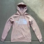 The North Face Hoodie Women’s Size XS Shade of Light Pink Has/Shows Wear, but still in good used condition overall Has all-over pilling/fuzzies Photo 1