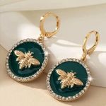 Earrings featuring a raised gold bee design on a glossy dark green background Photo 0