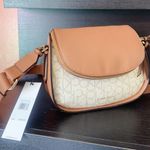 Calvin Klein unique flap camera bag brown vanilla wide soft strap crossbody NWT This crossbody bag is the perfect addition to any outfit. The bag features a unique flap closure with a zipper, magnetic, and snap closure options to ensure the safety of your belongings. The vanilla exterior leather material is accented with a strap accent, zipper, and flap closer, making it both stylish and functional. The bag has a medium size with a width of 11 inches, a height of 8 inches, and a depth of 5 inches. The hardware color is gold, while the handle/strap color is brown, adding a nice contrast to the bag. The bag also comes with an adjustable strap, making it easy to wear across the body. The interior features credit card slots, inner and outer pockets, organizers, and inner dividers, as well as a mobile phone pocket. The bag also comes with a brand card, and its product line is STYLE H4AEJEW4. New in box with tag Same day shipping Smoke and pets free Don’t forget to bundle In My Store Photo 0