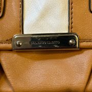 Franco Sarto tan and cream saddle style bag. Has a tear in the pocket inside