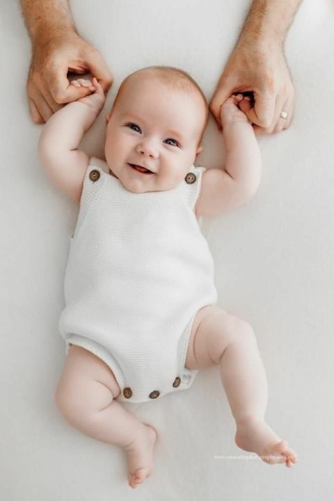 Joyful baby overhead shot smiling in white romper