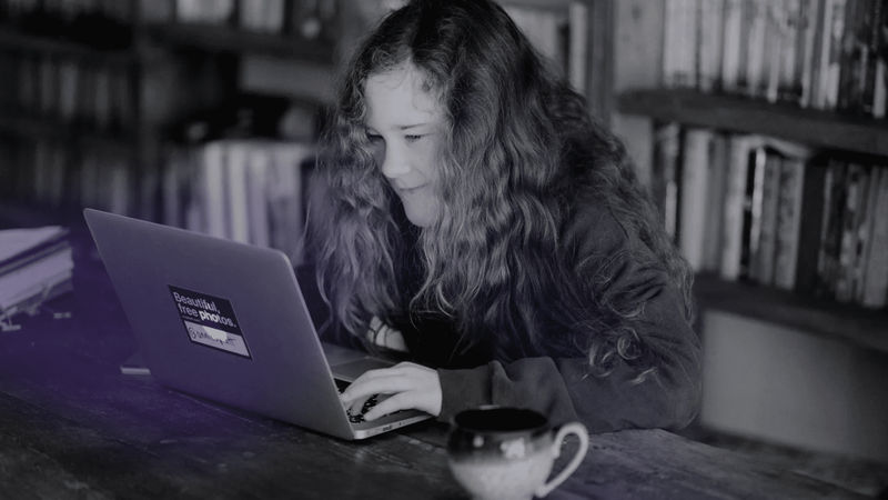 Woman smiling looking at her laptop, symbolizing the woman doing a coding challenge for beginners.