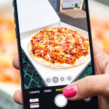 A person takiong a picture with their Iphone of the pizza.