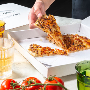 A BBQ Chicken pizza that is half eaten, a man is taking one of the last slices out of the box.