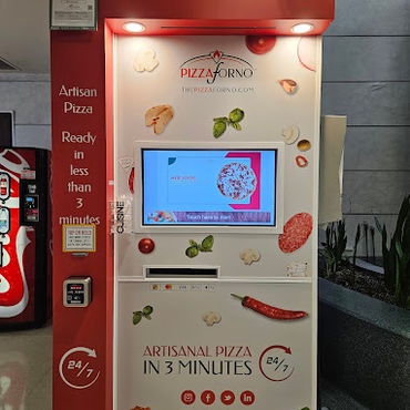 An indoor PizzaForno kiosk that has a vending machine beside it.