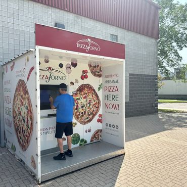 A man ordering pizza from a pizza vending machine