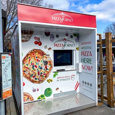 A pizza vending machine located outside with blue skies behind it.
