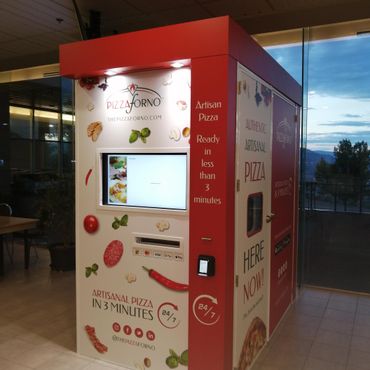 An indoor pizza vending machine in a dark room.