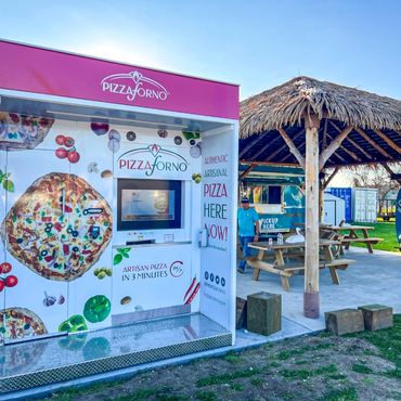 A pizza vending machine with a tiki hut beside it