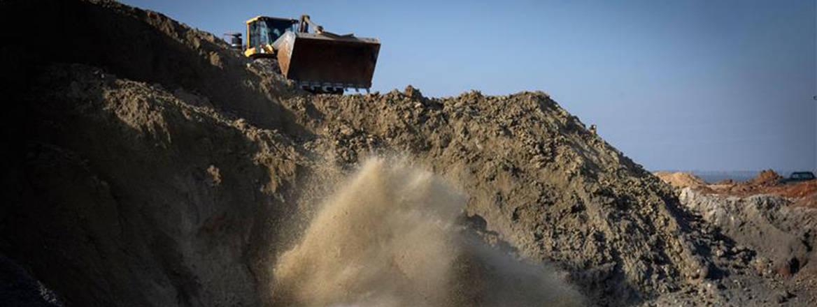 A bulldozer looms over a Ukrainian mine in Kirovohrad, as pressurized water extracts ilmenite down below, to be used in the production of titanium.