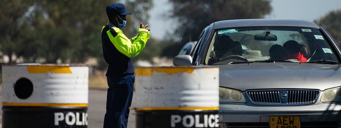A police officer in a Covid19 mask talks with a motorist at a checkpoint.