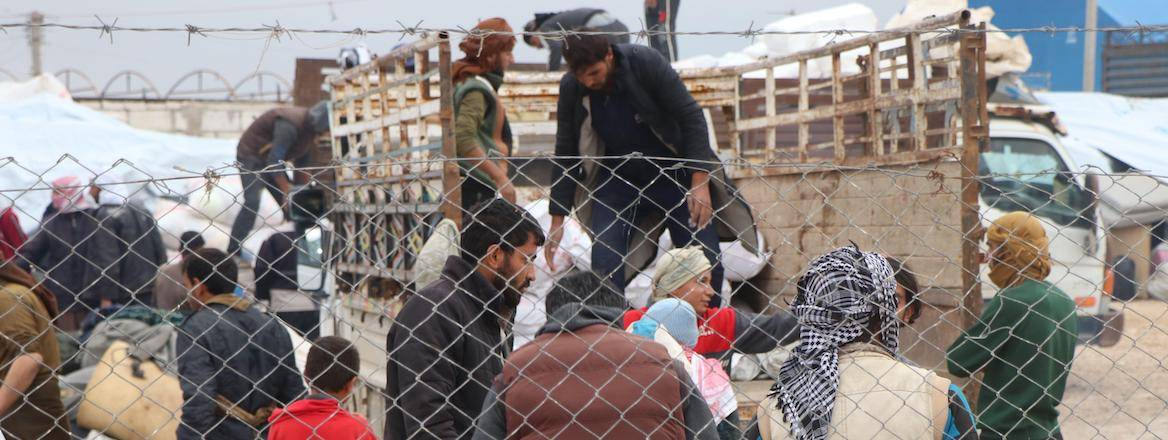 Displaced people are pictured behind a fence preparing to leave the Al-Hol camp, Syria, 16 November 2020