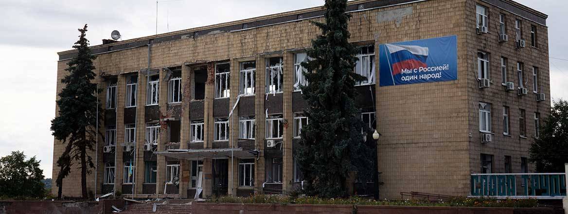 Three-storey brick building with Russian propaganda poster displayed